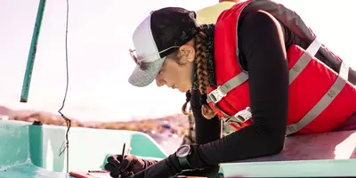 marine biologist in life jacket, on a yacht, making notes